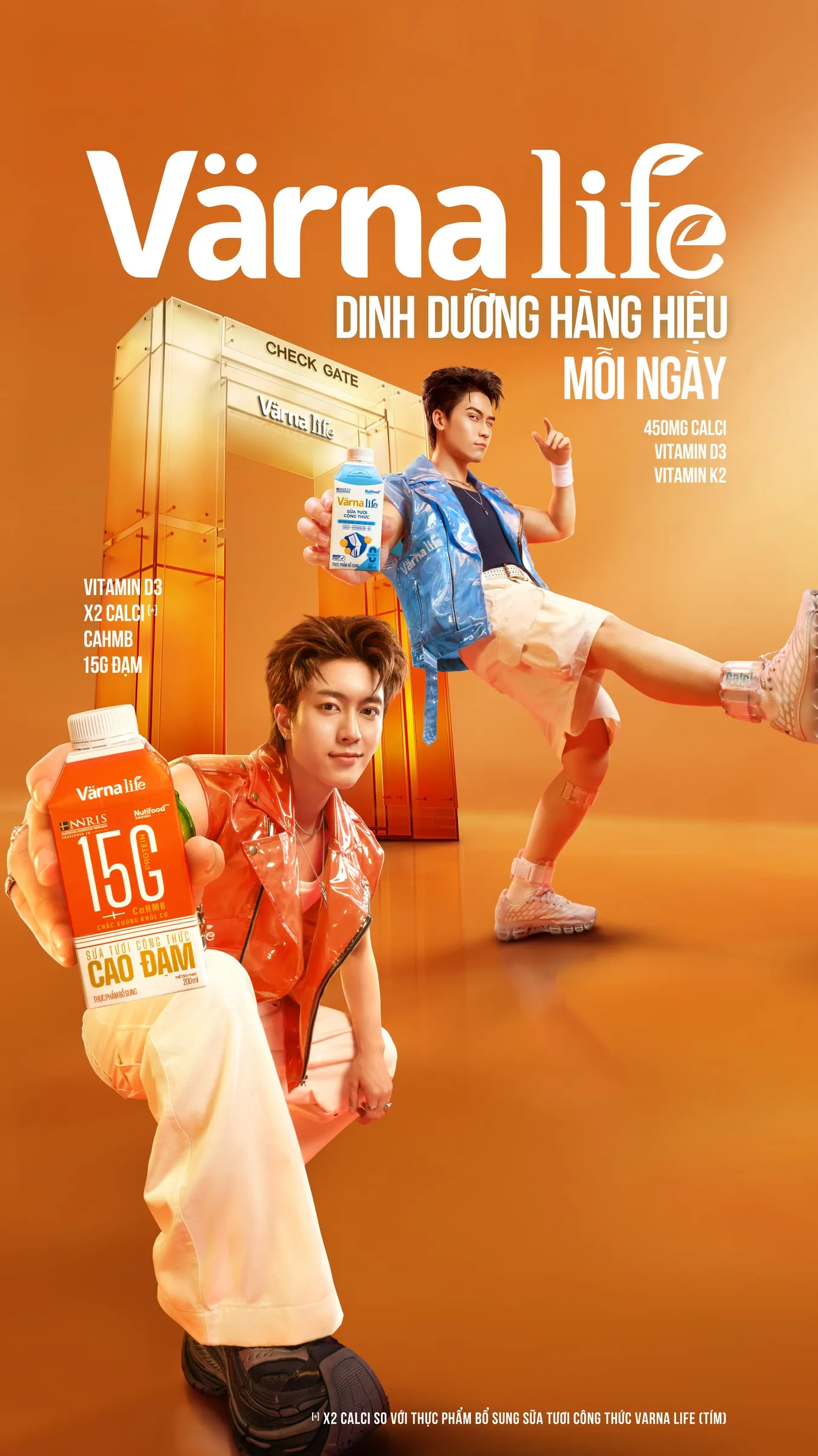 Hai người đàn ông trong trang phục rực rỡ ngồi trước tủ lạnh vàng, quảng bá vitamin cho thương hiệu Värna.